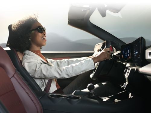 2024 Ford Mustang woman driving down the road with the car top off